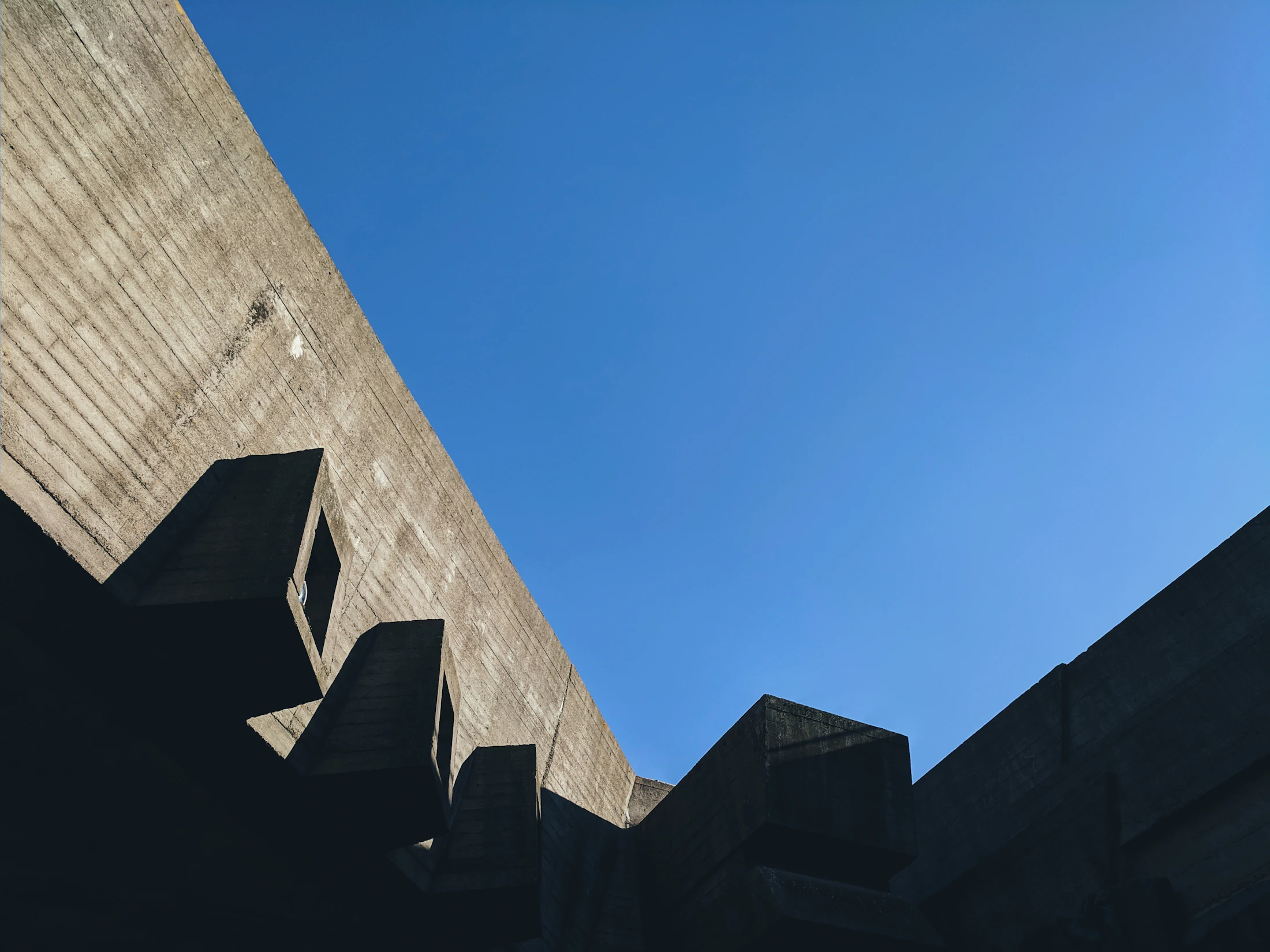 Minimal geometric forms of a gray concrete building under a blue sky
